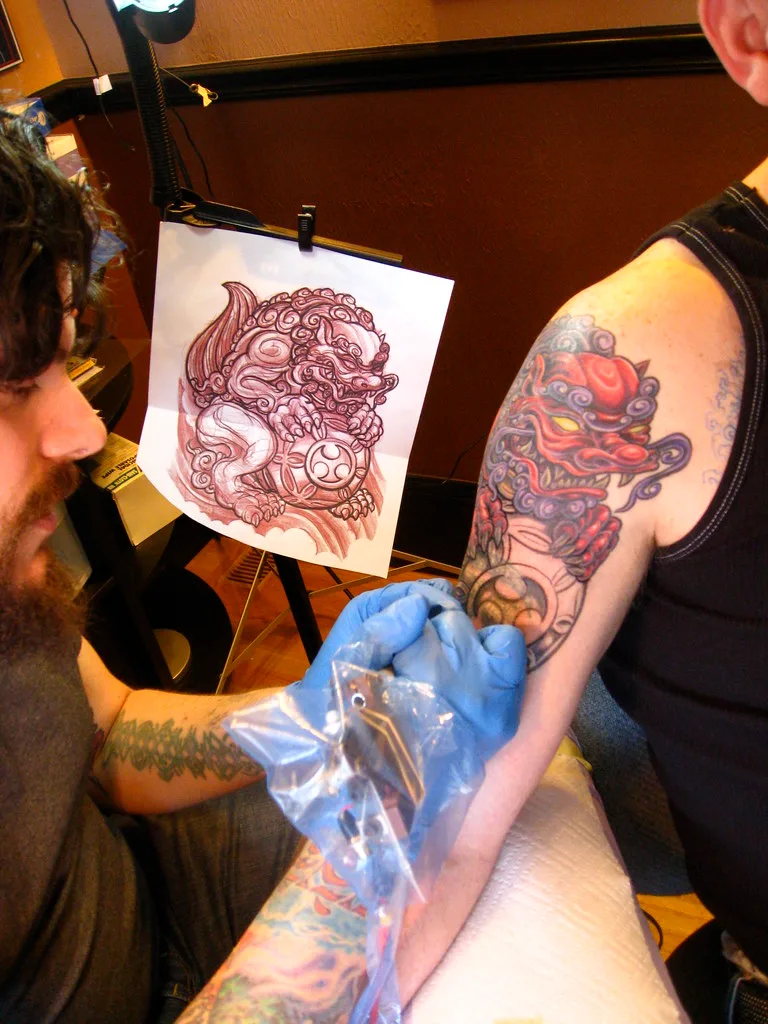 Tatuador comparando el stencil con el tatuaje en proceso